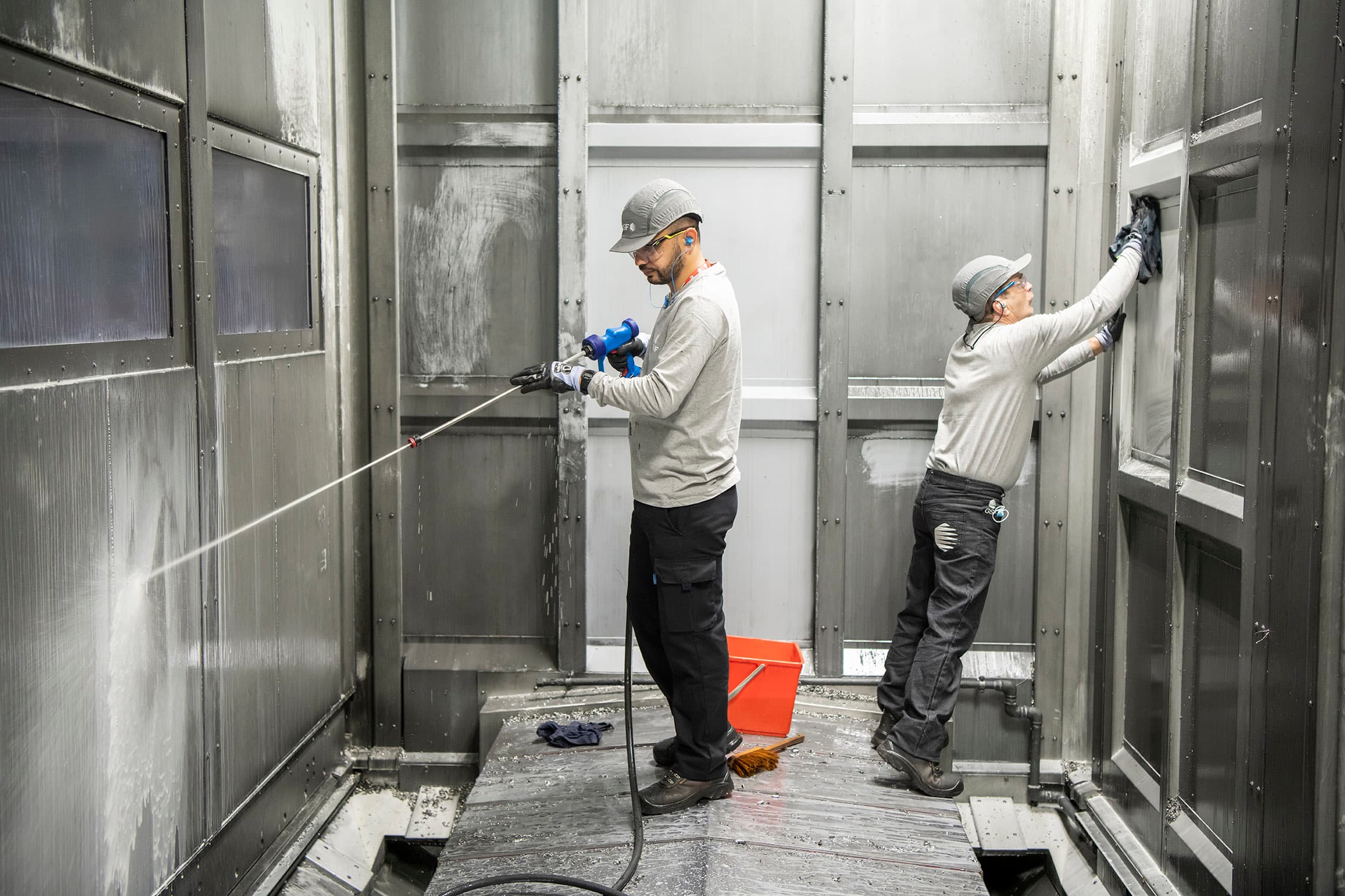 Deux intervenants GSF nettoyant l’intérieur d’une cabine de production.